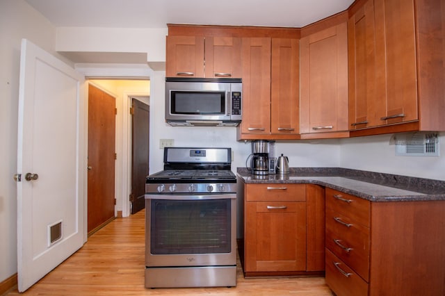 1904 Saunders Ave, Saint Paul, MN 55116 - kitchen featuring appliances with stainless steel finishes, light wood-style flooring, brown cabinets, and dark stone countertops