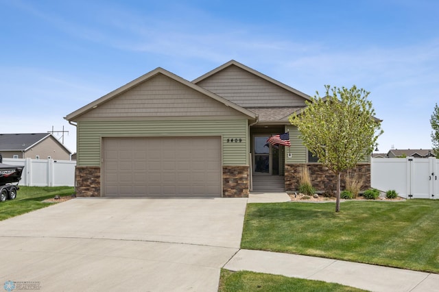 5409 47th Ave S, Fargo, ND 58104 - view of front of home with an attached garage, stone siding, a gate, and driveway