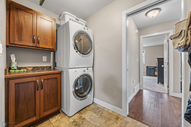 5409 47th Ave S, Fargo, ND 58104 - laundry room featuring stacked washer / drying machine, cabinet space, and baseboards