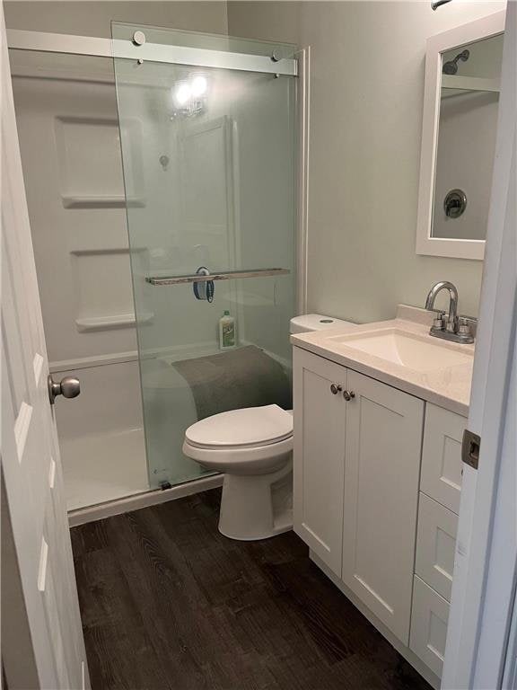 7354 72nd Ln N Unit 324, Brooklyn Park, MN 55428 - full bathroom featuring wood finished floors, a stall shower, toilet, and vanity