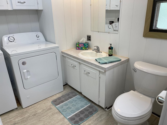 33008 Birch Ln, Motley, MN 56466 - half bathroom featuring vanity, toilet, washing machine and clothes dryer, a decorative wall, and wood finished floors