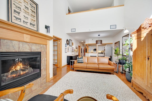 10014 Cove Dr, Hopkins, MN 55305 - living area featuring a tile fireplace, wood finished floors, a towering ceiling, and baseboards