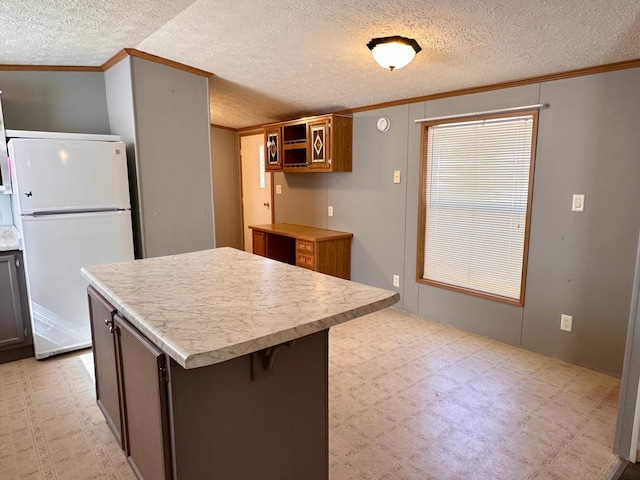 33363 Gardenview Dr, Sturgeon Lake, MN 55783 - kitchen with freestanding refrigerator, ornamental molding, a textured ceiling, light countertops, and a kitchen island