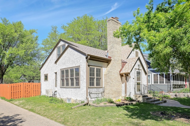view of front facade featuring a chimney, roof with shingles, cooling unit, and stucco siding