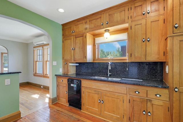 kitchen with black dishwasher, arched walkways, a wall mounted air conditioner, a sink, and light wood-style flooring