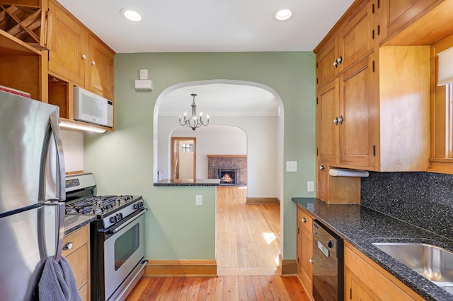 kitchen with appliances with stainless steel finishes, arched walkways, decorative backsplash, baseboards, and recessed lighting