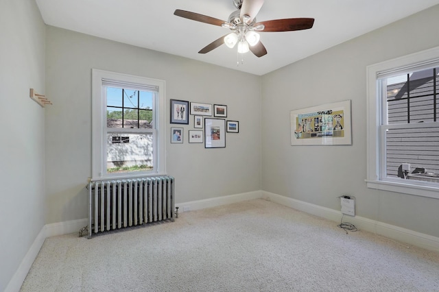 empty room with radiator, carpet floors, a ceiling fan, and baseboards