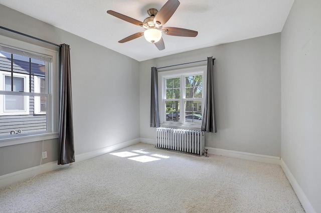 empty room featuring radiator heating unit, carpet floors, ceiling fan, and baseboards