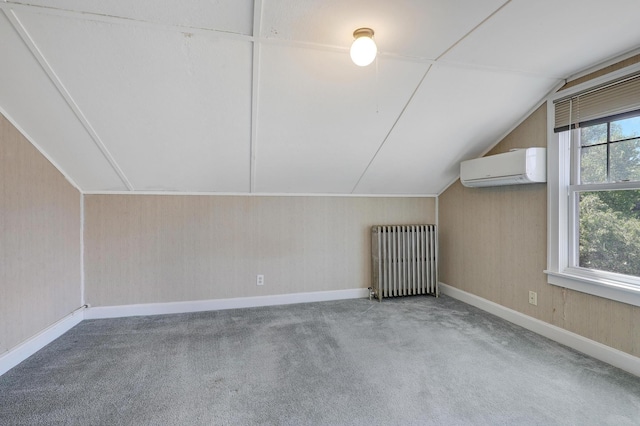 additional living space with radiator, a wall mounted air conditioner, vaulted ceiling, carpet flooring, and baseboards