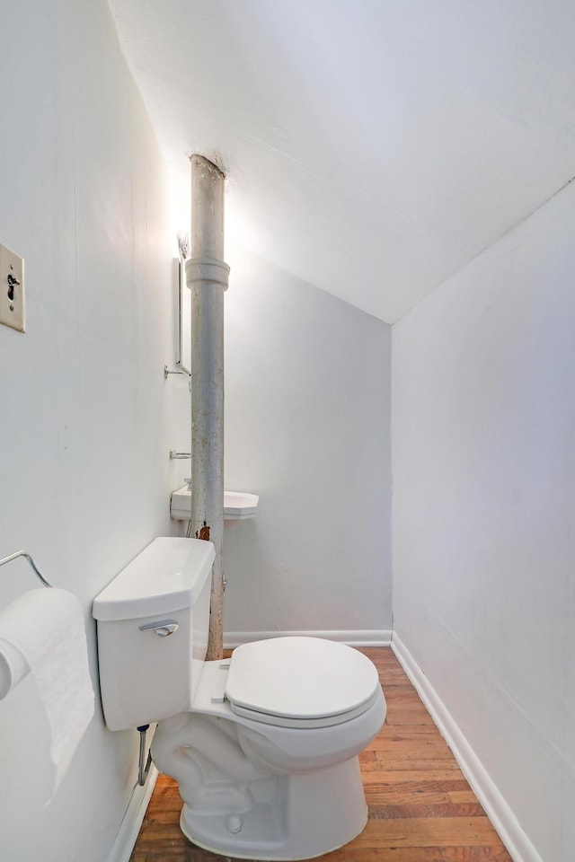 half bathroom featuring toilet, wood finished floors, and baseboards