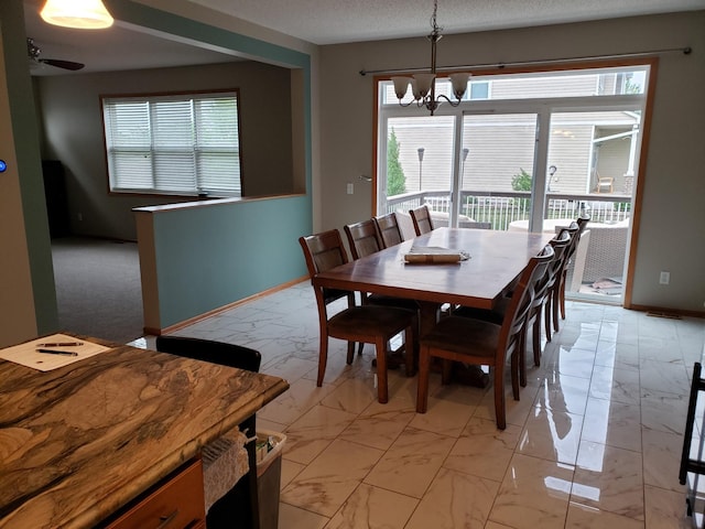 dining space featuring light marble finish floors, a chandelier, and baseboards