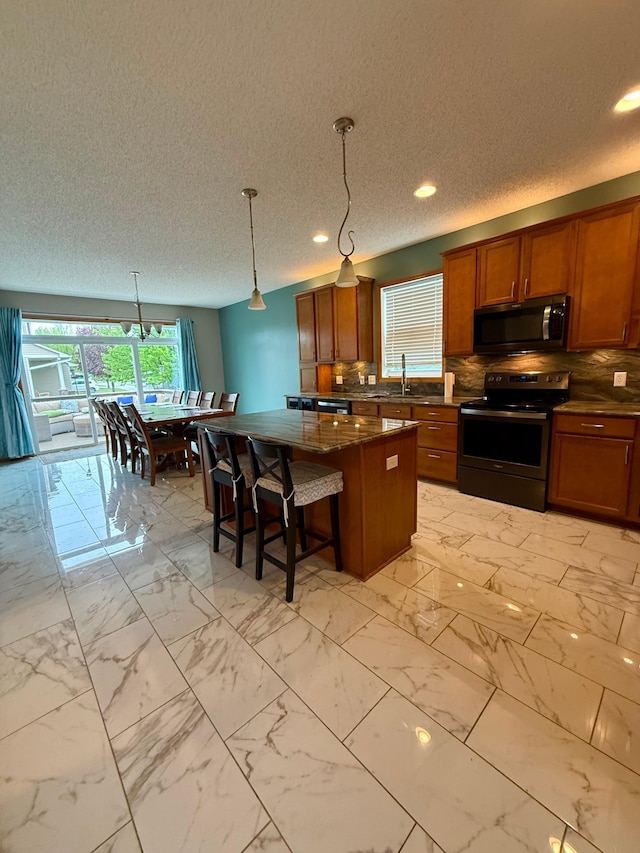 4681 Heritage Pkwy N, Hugo, MN 55038 - kitchen featuring appliances with stainless steel finishes, brown cabinets, a center island, a textured ceiling, and a sink