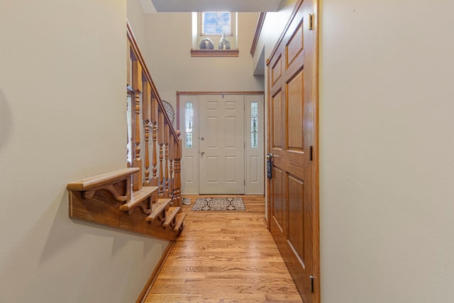 foyer featuring light wood finished floors, stairway, healthy amount of natural light, and a towering ceiling