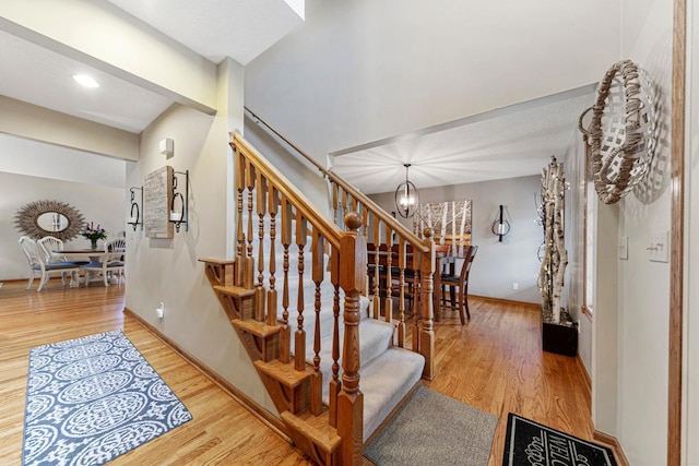 stairs featuring a chandelier, wood finished floors, baseboards, and recessed lighting
