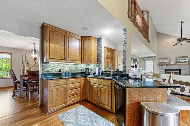 kitchen featuring a sink, dishwasher, ceiling fan, a peninsula, and light wood-style flooring