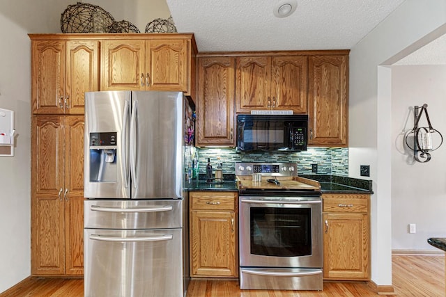 kitchen with stainless steel appliances, decorative backsplash, light wood-style flooring, brown cabinets, and a textured ceiling