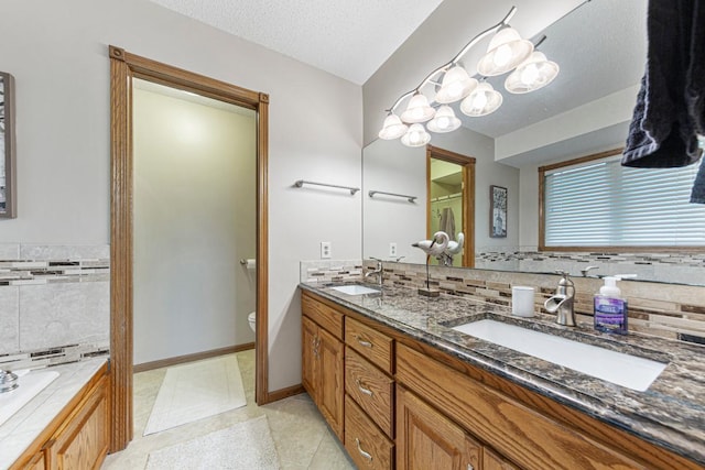 bathroom featuring toilet, double vanity, a garden tub, and decorative backsplash