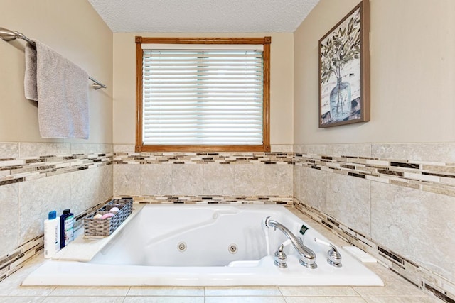 bathroom with a tub with jets, a textured ceiling, and wainscoting