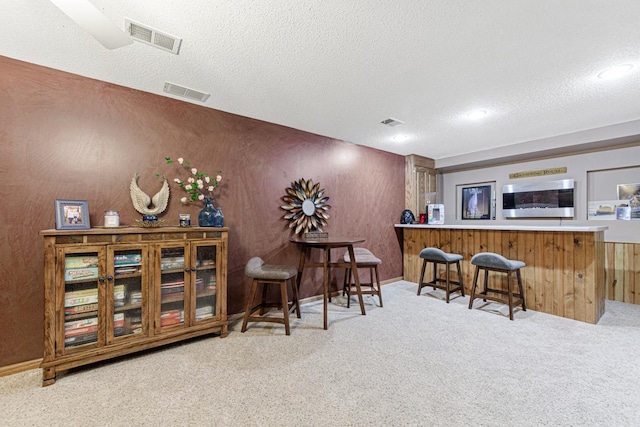 indoor dry bar with a textured ceiling, carpet floors, and recessed lighting