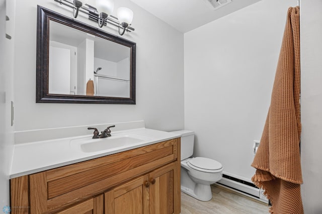 2514 Willow Rd N, Fargo, ND 58102 - full bathroom featuring baseboard heating, toilet, vanity, and wood finished floors