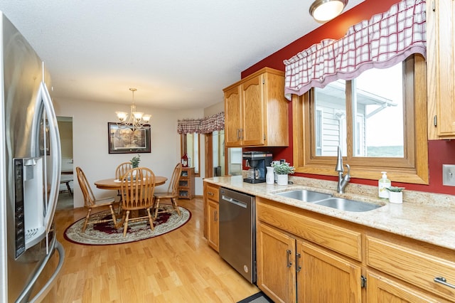 4822 3rd St NW, Rochester, MN 55901 - kitchen featuring appliances with stainless steel finishes, a sink, light wood finished floors, a chandelier, and light stone countertops