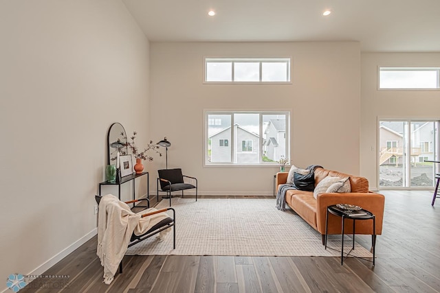 sitting room with wood finished floors, a high ceiling, recessed lighting, and baseboards