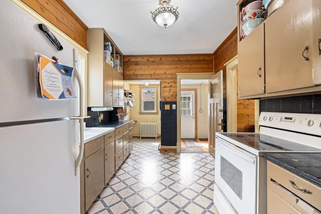 301 3rd St, Nashwauk, MN 55769 - kitchen featuring white appliances, radiator heating unit, wood walls, light floors, and decorative backsplash