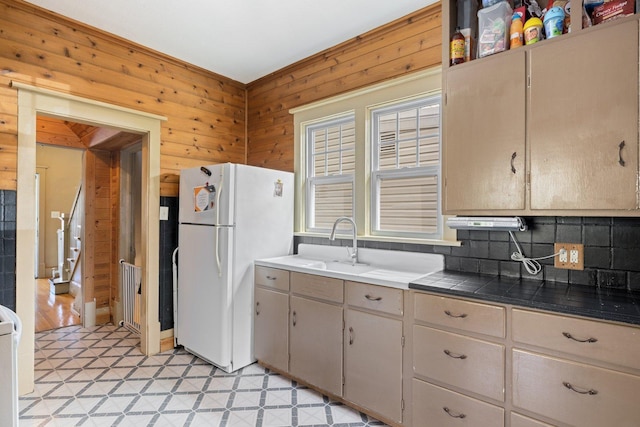 301 3rd St, Nashwauk, MN 55769 - kitchen featuring freestanding refrigerator, backsplash, wood walls, light flooring, and a sink