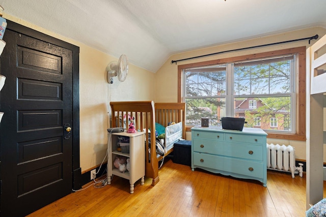 301 3rd St, Nashwauk, MN 55769 - bedroom with radiator heating unit, lofted ceiling, and light wood-style floors