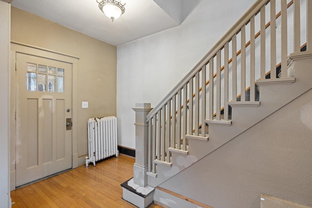 301 3rd St, Nashwauk, MN 55769 - entryway featuring radiator, hardwood / wood-style flooring, stairway, and baseboards
