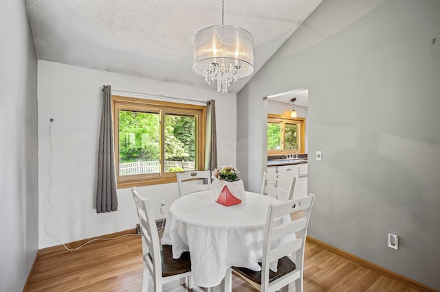 1653 Briardale Rd NE, Fridley, MN 55432 - dining room featuring a chandelier, lofted ceiling, light wood finished floors, baseboards, and a textured ceiling
