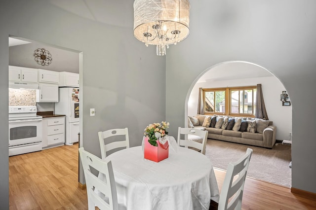 1653 Briardale Rd NE, Fridley, MN 55432 - dining area with arched walkways, a high ceiling, a chandelier, and light wood-style floors