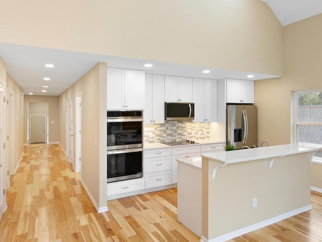 17394 Sunset Trl SW, Prior Lake, MN 55372 - kitchen featuring appliances with stainless steel finishes, tasteful backsplash, light countertops, a center island with sink, and light wood-style flooring