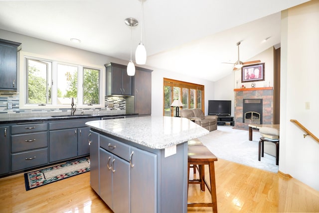 kitchen featuring a sink, healthy amount of natural light, a fireplace, a kitchen breakfast bar, and lofted ceiling