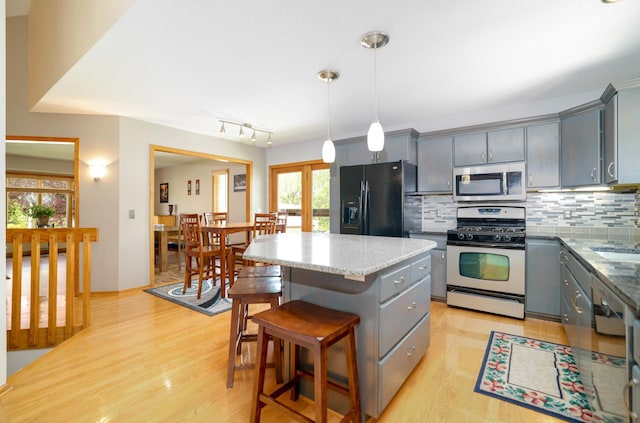 kitchen with stainless steel appliances, gray cabinetry, a center island, and backsplash