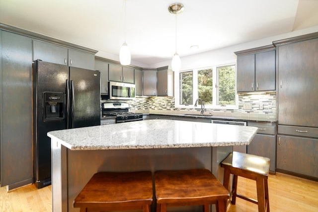 kitchen featuring appliances with stainless steel finishes, a sink, decorative backsplash, and a kitchen breakfast bar