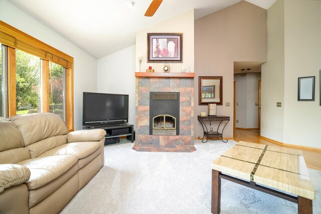 carpeted living room featuring vaulted ceiling, a fireplace, and a ceiling fan