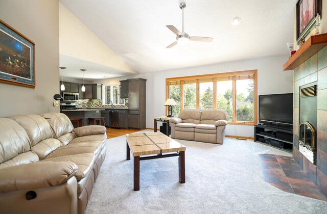 living room with a tile fireplace, ceiling fan, plenty of natural light, high vaulted ceiling, and baseboards