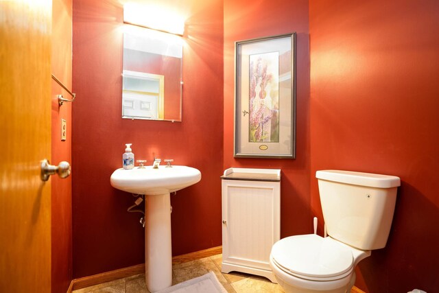 bathroom featuring toilet, baseboards, and a sink