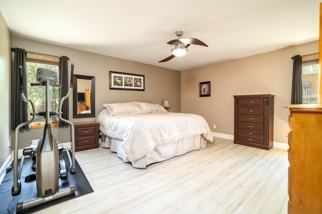 bedroom with light wood finished floors, baseboards, and ceiling fan