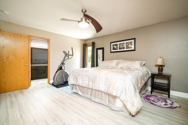 bedroom featuring wood finished floors, baseboards, ceiling fan, and ensuite bathroom