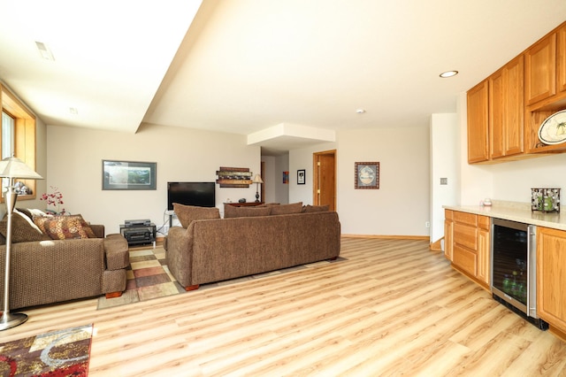 living area featuring beverage cooler, light wood-type flooring, a bar, baseboards, and recessed lighting
