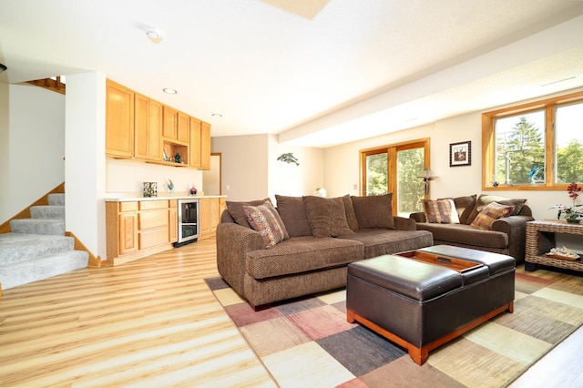 living room featuring wine cooler, light wood-style flooring, bar, stairs, and recessed lighting