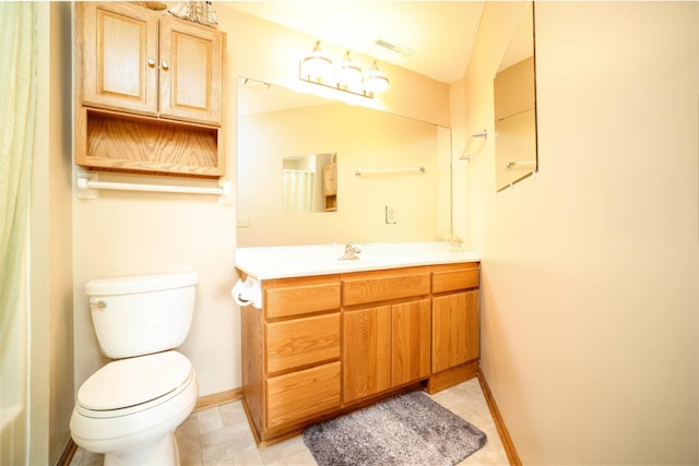 bathroom featuring baseboards, toilet, and vanity