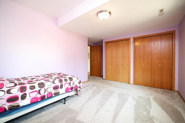 bedroom with carpet and two closets