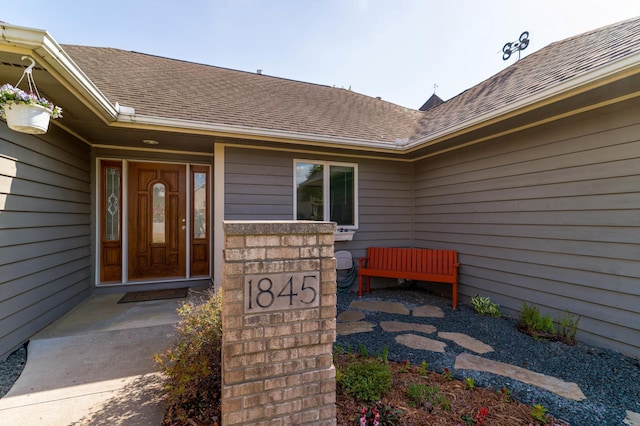 doorway to property with roof with shingles