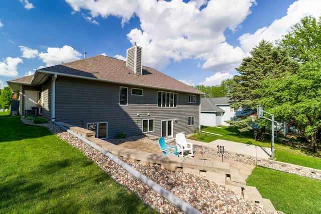 rear view of house featuring a chimney, a patio area, a yard, and a shingled roof