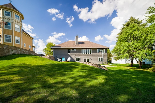 rear view of house featuring a chimney and a yard