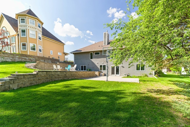 back of house featuring a patio area, a chimney, and a lawn