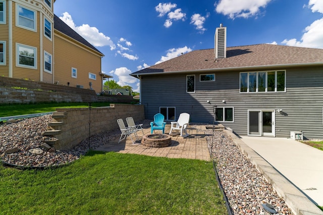 rear view of house featuring a fire pit, a chimney, a patio area, a yard, and a shingled roof